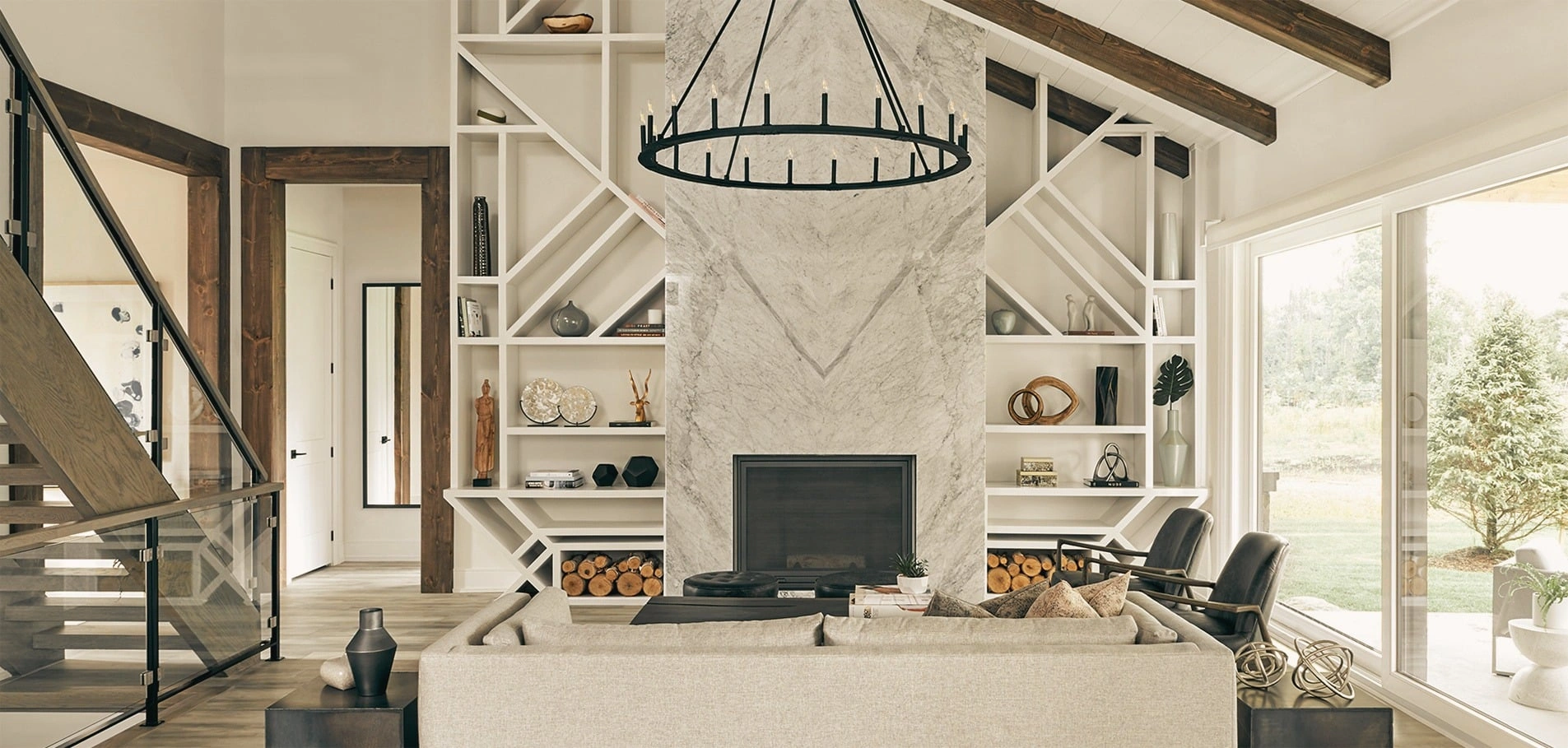 A bright living room with a stone fireplace, open shelving and large windows.