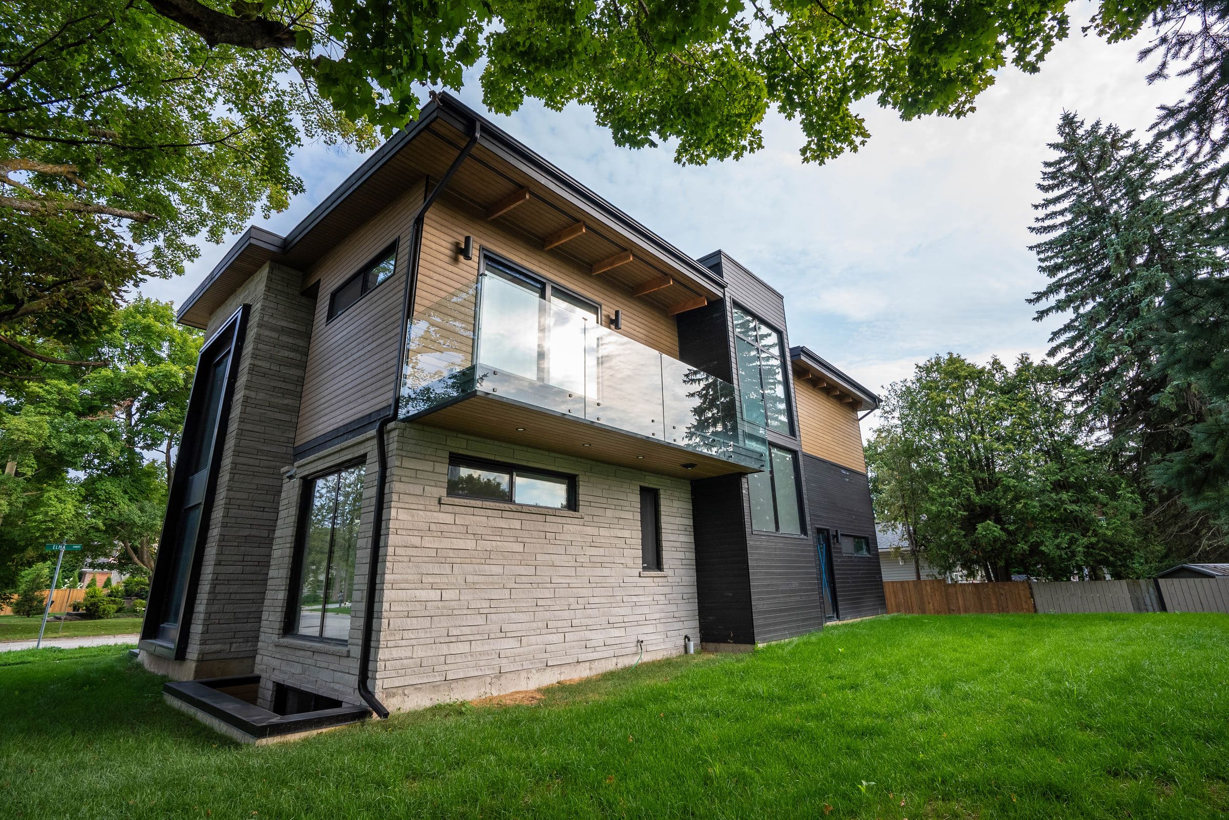 Glass-railed balcony above stone walls beside the dark-clad side elevation.