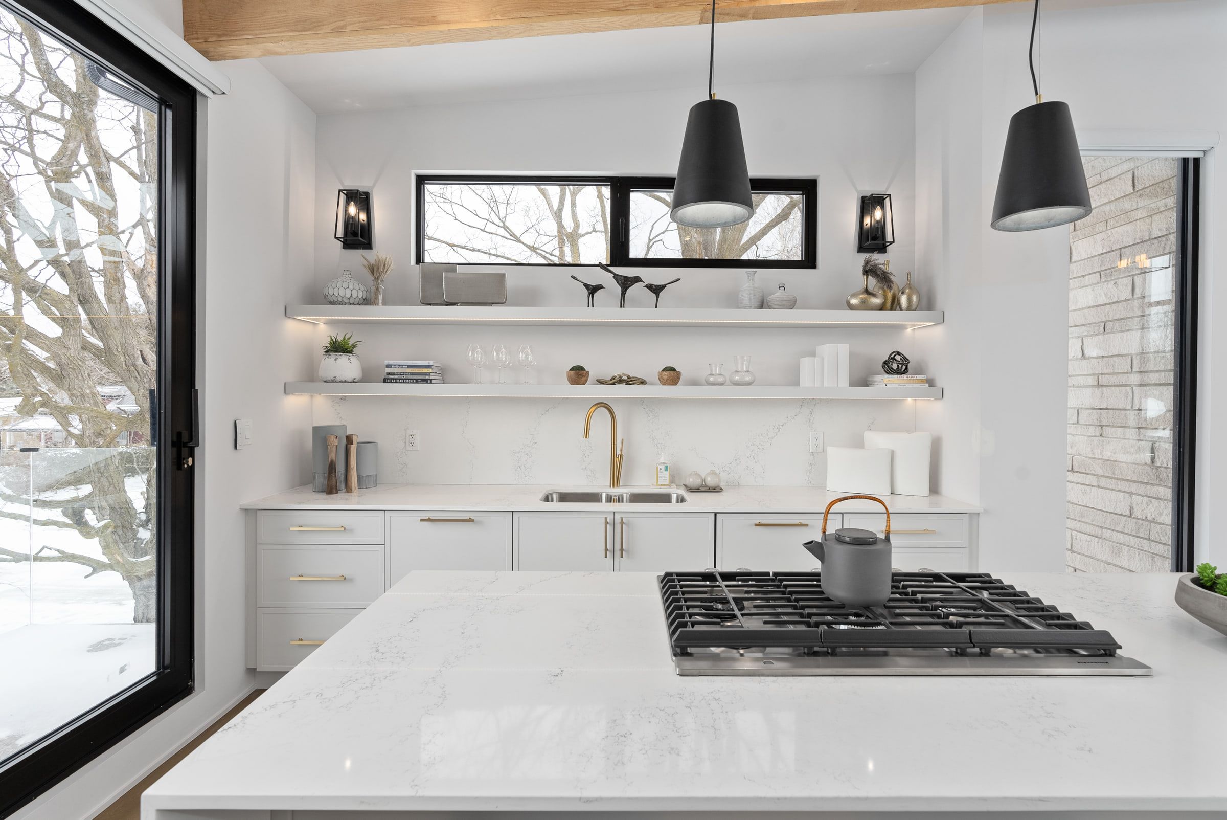 Kitchen range wall with open shelving, a brass tap and light cabinetry.