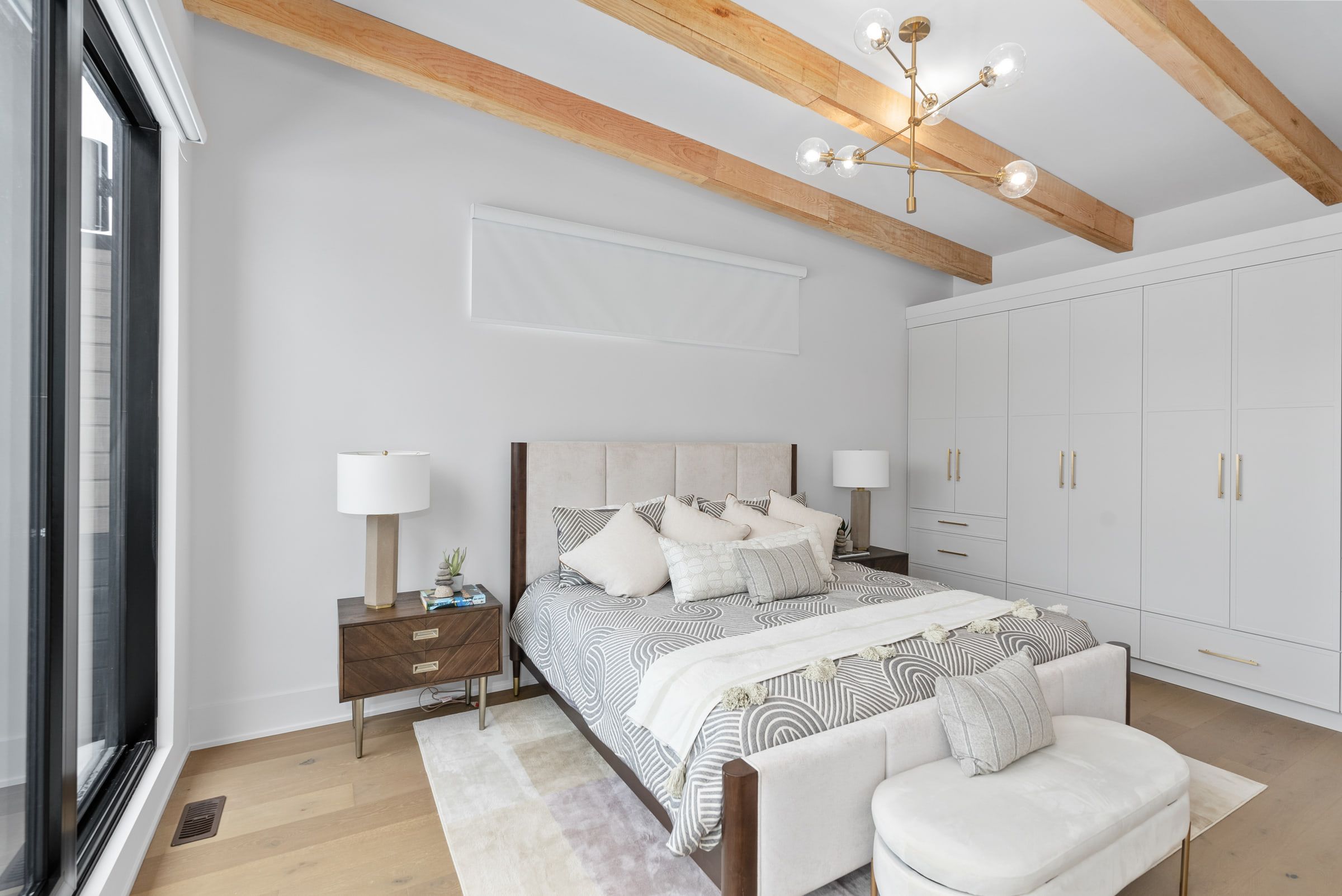 Primary bedroom with exposed ceiling beams and a built-in wardrobe.