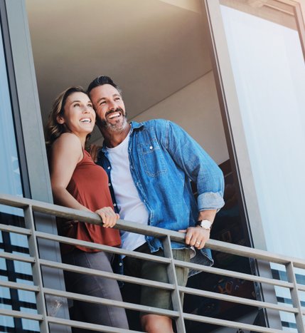 A smiling couple on their balcony at Q1 Condos.